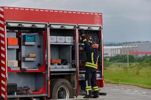 A firefighter meticulously prepares a modern firetruck for a mission to evacuate and respond to dangerous situations, showcasing the utmost dedication to safety and readiness in the face of a fire photo