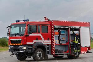 A firefighter meticulously prepares a modern firetruck for a mission to evacuate and respond to dangerous situations, showcasing the utmost dedication to safety and readiness in the face of a fire photo