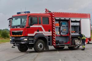 A firefighter meticulously prepares a modern firetruck for a mission to evacuate and respond to dangerous situations, showcasing the utmost dedication to safety and readiness in the face of a fire photo