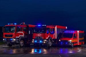 A pair of highly modern and quality fire trucks illuminate the night with their rotating lights, symbolizing the cutting-edge technology and preparedness of the firefighting fleet, ready to respond to photo