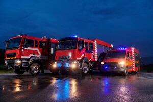 A pair of highly modern and quality fire trucks illuminate the night with their rotating lights, symbolizing the cutting-edge technology and preparedness of the firefighting fleet, ready to respond to photo