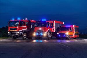 A pair of highly modern and quality fire trucks illuminate the night with their rotating lights, symbolizing the cutting-edge technology and preparedness of the firefighting fleet, ready to respond to photo