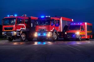 A pair of highly modern and quality fire trucks illuminate the night with their rotating lights, symbolizing the cutting-edge technology and preparedness of the firefighting fleet, ready to respond to photo