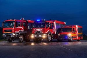 A pair of highly modern and quality fire trucks illuminate the night with their rotating lights, symbolizing the cutting-edge technology and preparedness of the firefighting fleet, ready to respond to photo