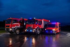 A pair of highly modern and quality fire trucks illuminate the night with their rotating lights, symbolizing the cutting-edge technology and preparedness of the firefighting fleet, ready to respond to photo