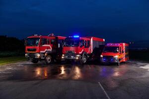 A pair of highly modern and quality fire trucks illuminate the night with their rotating lights, symbolizing the cutting-edge technology and preparedness of the firefighting fleet, ready to respond to photo
