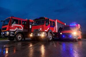 A pair of highly modern and quality fire trucks illuminate the night with their rotating lights, symbolizing the cutting-edge technology and preparedness of the firefighting fleet, ready to respond to photo