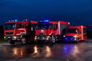 A pair of highly modern and quality fire trucks illuminate the night with their rotating lights, symbolizing the cutting-edge technology and preparedness of the firefighting fleet, ready to respond to photo