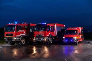 A pair of highly modern and quality fire trucks illuminate the night with their rotating lights, symbolizing the cutting-edge technology and preparedness of the firefighting fleet, ready to respond to photo