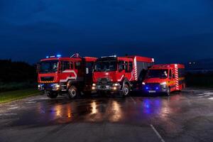 A pair of highly modern and quality fire trucks illuminate the night with their rotating lights, symbolizing the cutting-edge technology and preparedness of the firefighting fleet, ready to respond to photo