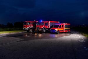 A pair of highly modern and quality fire trucks illuminate the night with their rotating lights, symbolizing the cutting-edge technology and preparedness of the firefighting fleet, ready to respond to photo