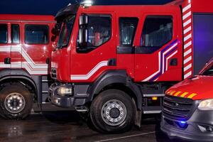 A pair of highly modern and quality fire trucks illuminate the night with their rotating lights, symbolizing the cutting-edge technology and preparedness of the firefighting fleet, ready to respond to photo