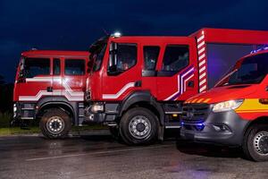 A pair of highly modern and quality fire trucks illuminate the night with their rotating lights, symbolizing the cutting-edge technology and preparedness of the firefighting fleet, ready to respond to photo