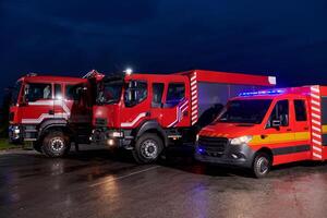 A pair of highly modern and quality fire trucks illuminate the night with their rotating lights, symbolizing the cutting-edge technology and preparedness of the firefighting fleet, ready to respond to photo