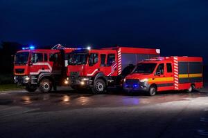 A pair of highly modern and quality fire trucks illuminate the night with their rotating lights, symbolizing the cutting-edge technology and preparedness of the firefighting fleet, ready to respond to photo