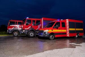 A pair of highly modern and quality fire trucks illuminate the night with their rotating lights, symbolizing the cutting-edge technology and preparedness of the firefighting fleet, ready to respond to photo