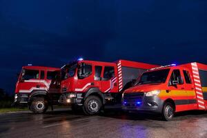 A pair of highly modern and quality fire trucks illuminate the night with their rotating lights, symbolizing the cutting-edge technology and preparedness of the firefighting fleet, ready to respond to photo