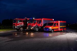 A pair of highly modern and quality fire trucks illuminate the night with their rotating lights, symbolizing the cutting-edge technology and preparedness of the firefighting fleet, ready to respond to photo