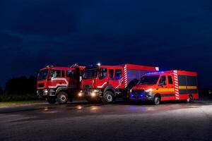 A pair of highly modern and quality fire trucks illuminate the night with their rotating lights, symbolizing the cutting-edge technology and preparedness of the firefighting fleet, ready to respond to photo