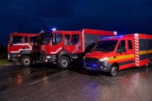 A pair of highly modern and quality fire trucks illuminate the night with their rotating lights, symbolizing the cutting-edge technology and preparedness of the firefighting fleet, ready to respond to photo
