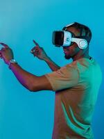 Immersed in a digital realm, an African American man navigates the virtual landscape with a VR goggles, using tactile gestures to interact with virtual objects, showcasing a harmonious blend of photo