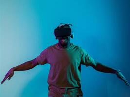 African American man dons VR glasses, engrossed in a virtual reality simulation, gesturing with hands, against a striking blue background, highlighting the fusion of cutting-edge technology and photo