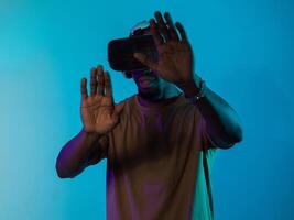 Immersed in a digital realm, an African American man navigates the virtual landscape with a VR goggles, using tactile gestures to interact with virtual objects, showcasing a harmonious blend of photo