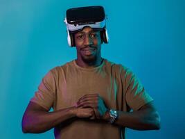 In an avant-garde scene, an African American man engages in cutting-edge virtual reality gaming, utilizing VR glasses to immerse himself in futuristic boxing games, set against a vivid blue background photo