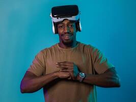 In an avant-garde scene, an African American man engages in cutting-edge virtual reality gaming, utilizing VR glasses to immerse himself in futuristic boxing games, set against a vivid blue background photo