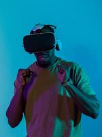 African American man immerses himself in a thrilling horror gaming experience using VR glasses, creating an isolated and intense atmosphere against a striking blue background photo