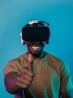 African American man wearing virtual reality glasses expresses satisfaction and impressed delight, gesturing with his hand pointed upward, while standing isolated against a vibrant yellow background photo