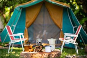 selective focus of vintage coffee set on the old wooden table In front of the retro cabin tent, retro chairs, Group of camping tents, and soft focus. photo