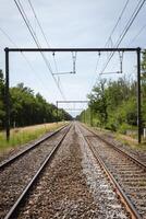 electrified railway tracks with wires countryside lanscape perspective sunny day photo