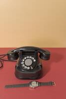 Retro phone from 60s 70s and retro watch with leather strap. On a red-orange background photo