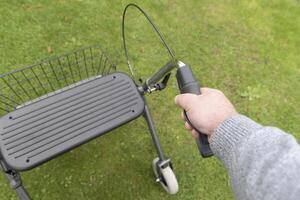 A man holding on to the left handle of a rollator. Using Walker Rollator view from above. photo