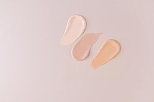 Three beautiful samples of foundation powder of different tones on a beige background with a copy space. Delicate texture of foundation . top view. photo