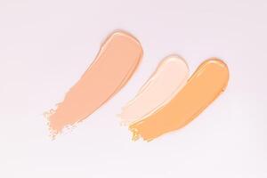 Three strokes of foundation powder of different tones on a white background. samples of the texture of the cosmetic product. Texture of foundation. photo