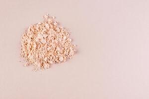 A pile of loose light powder on a beige background. space for text. layout for your product. Color cosmetics texture concept. Top view. photo