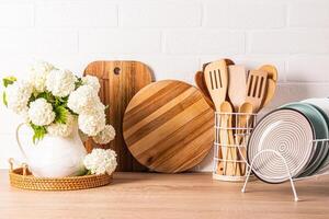 Beautiful kitchen background with kitchen utensils and eco-friendly utensils on a wooden countertop with a pitcher of white spring flowering branches. photo