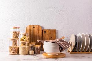 A beautiful kitchen background with a storage area for bulk products in glass jars, plates in the dryer, a large bowl on a marble countertop. photo