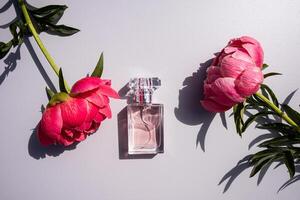 Elegant bottle of women's perfume with delicate fragrances on a gray background with flowers peonies pink . Empty packaging. presentation. photo