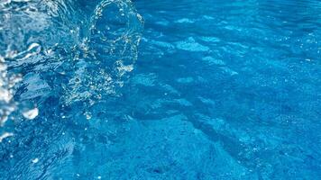 Background dynamic splash of clear water creating swirling wave in blue water with droplets suspended in motion. Clean water concept. photo