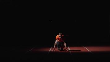 Professional Sprinter Runner Starting From Low Start Position In Dark Stadium, Frontal View video