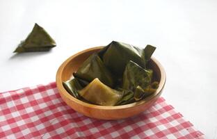 Bugis cake, traditional Indonesian food in the form of cake made from sticky rice flour filled with sweet grated coconut and wrapped in banana leaves. photo