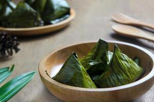 Bugis cake, traditional Indonesian food in the form of cake made from sticky rice flour filled with sweet grated coconut and wrapped in banana leaves. photo