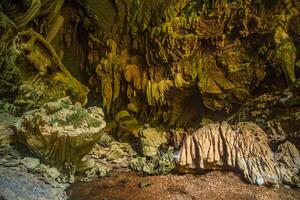 The beautiful views of the stalactite and stalagmite-filled cave in Lam Khlong Ngu National Park, Thailand. At the cave's exit is a small waterfall also. photo