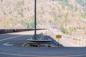 The scene of the road at the top of the dam, with the mountains in the background and a light pole. photo