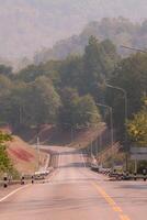 The scene of the road at the dam, with the mountains in the background and a light pole. photo