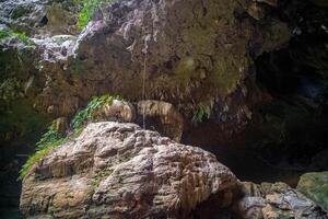 The beautiful views of the stalactite and stalagmite-filled cave in Lam Khlong Ngu National Park, Thailand. At the cave's exit is a small waterfall also. photo