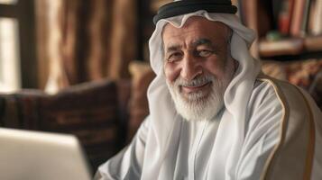 Portrait of a Smiling Elderly Middle Eastern Man in Traditional Attire, Seated at a Desk with Books in the Background photo